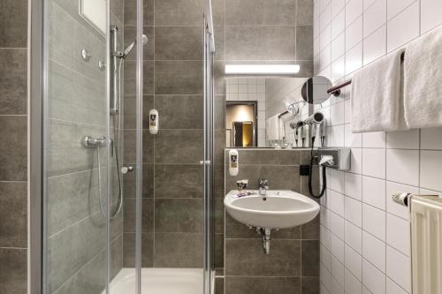 斯图加特斯图加特祖福豪森美居酒店的一间带水槽和玻璃淋浴的浴室