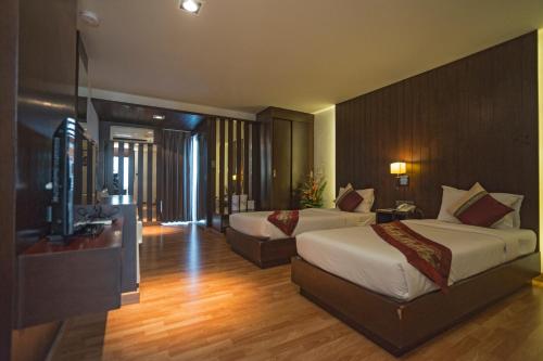 合艾Kiss Gardenhome Chic Hotel的酒店客房设有两张床和电视。
