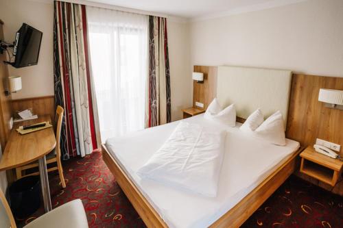 埃赫施塔特福克斯加尼酒店的一间酒店客房,配有一张白色的床和一张书桌