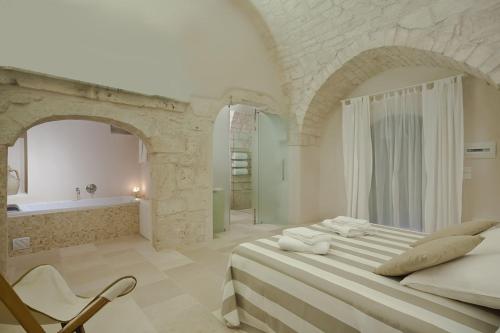 奥斯图尼马雷斯卡农家乐的白色卧室设有一张大床和浴缸