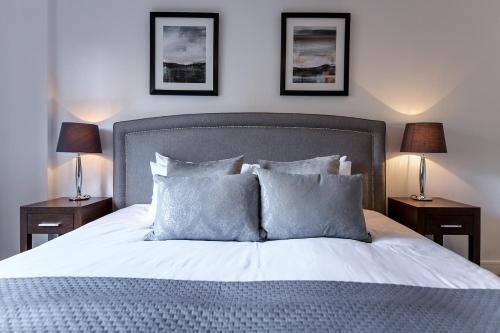 伦敦阿尔德盖特城市公寓的一间卧室配有一张带枕头的床和两盏灯。