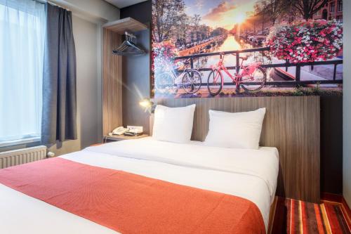 阿姆斯特丹莫扎特酒店的酒店客房设有一张床,墙上挂有绘画作品