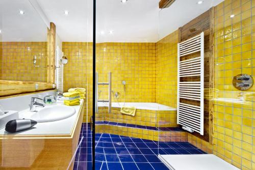 米特西尔科格勒运动酒店的浴室设有黄色瓷砖、浴缸和水槽