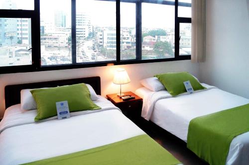 瓜亚基尔卡斯特利酒店的带大窗户的客房内的两张床