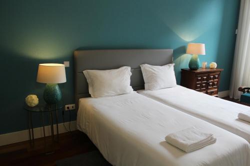 波尔图波尔图历史公寓的一间卧室配有两张带白色床单和两盏灯的床。