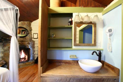 阿什维尔The Pines Cottages的一间带壁炉、水槽和镜子的浴室