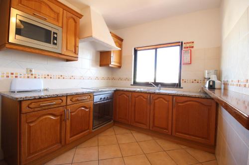 阿尔布费拉Dinita Apartamento nº4的厨房配有木制橱柜、水槽和窗户。