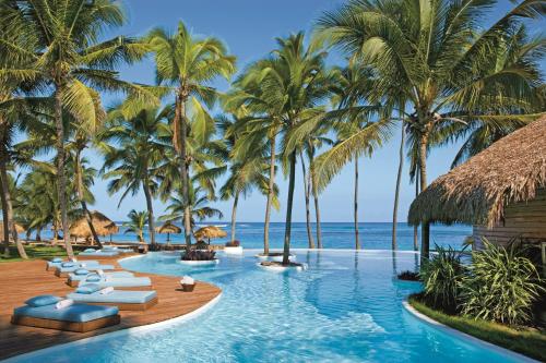 蓬塔卡纳Zoetry Agua Punta Cana - All Inclusive的一个带躺椅和棕榈树的无边际游泳池
