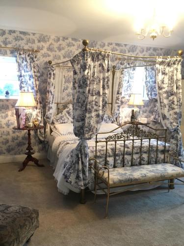 本拉提Rossmanagher House的一间卧室配有一张天蓬床,拥有蓝色和白色的壁纸