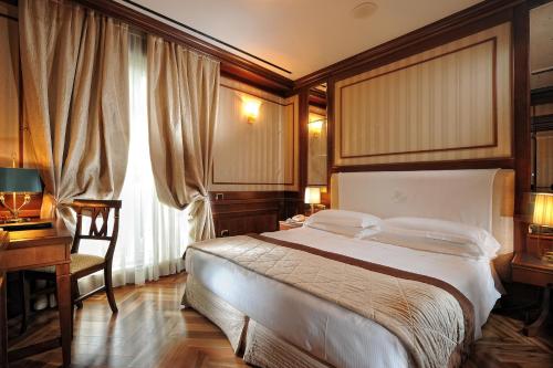 米兰曼佐尼酒店的一间卧室配有一张大床、一张书桌和一个窗户。