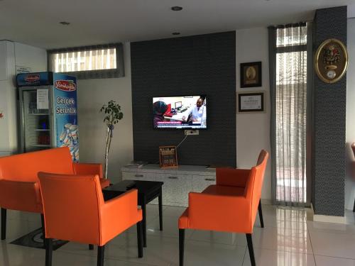 安塔利亚Mutado Hotel的用餐室配有橙色椅子和墙上的电视