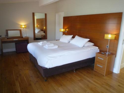 卡斯尔马特Castlemartyr Holiday Lodges 2 Bed的卧室配有一张白色大床和木制床头板