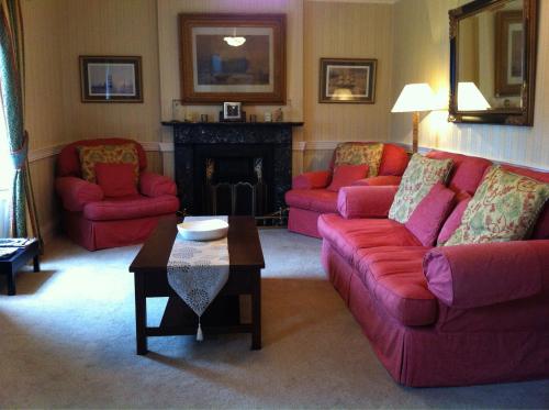 卡林福德Carlingford House Town House Accommodation A91 TY06的客厅设有2张红色的沙发和壁炉