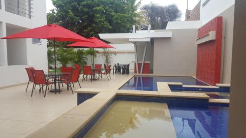San Juan del CesarCasa Murillo Hotel的一个带桌椅和红色遮阳伞的游泳池