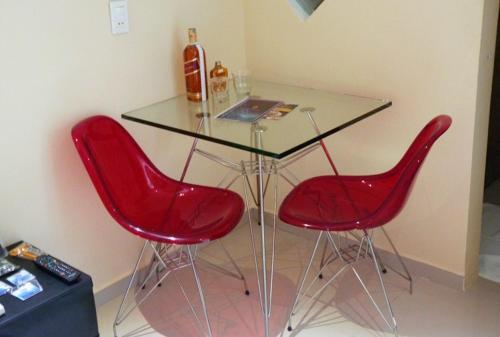 累西腓Rhodes Hotel Recife的一张玻璃桌,配有两把红色椅子和一瓶葡萄酒