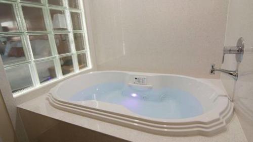 瓦列霍丽晶酒店的带窗户的浴室内的白色浴缸