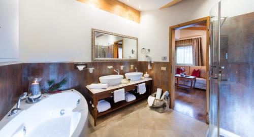 阿尔卑斯休斯山Hotel Rosa Eco Alpine Spa Resort的浴室设有2个水槽、浴缸和镜子