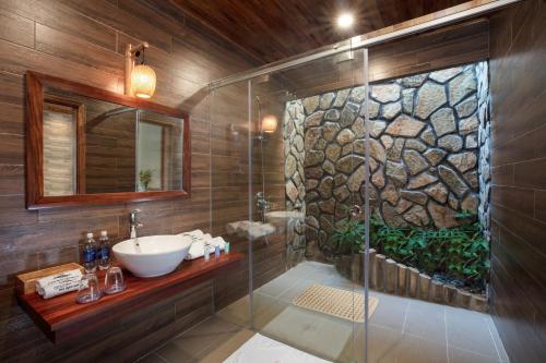 富国富国戈尔登托帕兹度假村的浴室配有水槽和带石墙的淋浴