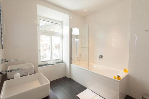 维森Boutique-Hotel Garni Bellevue Davos Wiesen的白色的浴室设有浴缸和水槽。