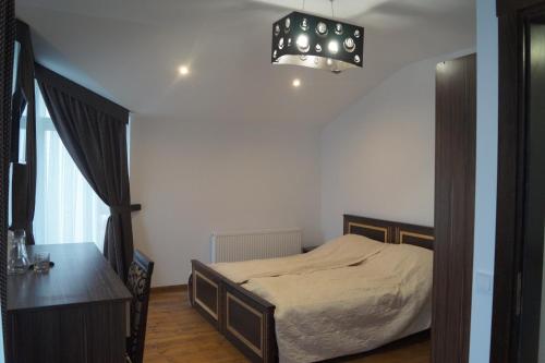 莫申VillaMaria的一间卧室配有一张床、一张桌子和一个吊灯。