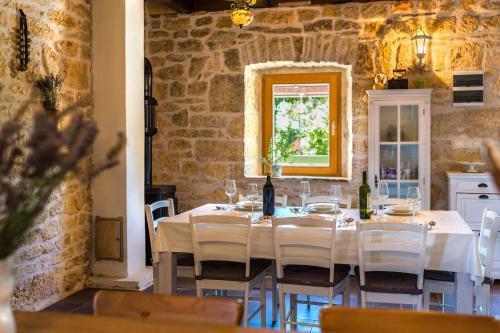 BogatićRural house Mudrinic "Ivini dvori"的用餐室配有带白色椅子的桌子和窗户