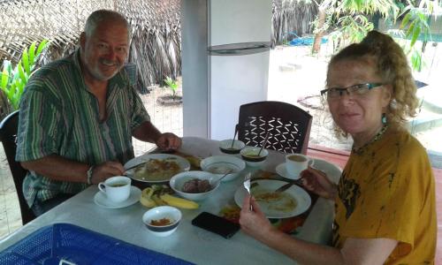 拜蒂克洛Naaval Beach Villa & Rooms的坐在餐桌旁吃食物的男人和女人