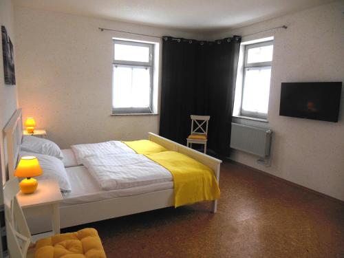 HottelstedtFeWo Hottelstedt的一间卧室配有一张带黄毯的床和两个窗户