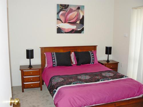 杰拉尔顿Geraldton Luxury Retreat 2 with free Streaming的一间卧室配有粉红色的床和2个床头柜