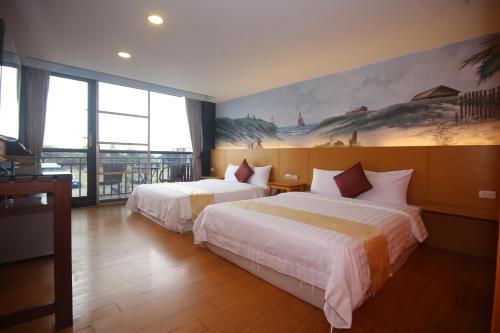 垦丁大街垦丁水岸海景渡假旅店的酒店客房设有两张床,墙上挂有绘画作品