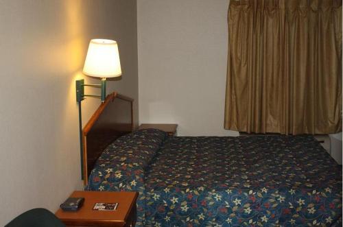 梅普尔伍德翡翠汽车旅馆的一间卧室配有一张床、一盏灯和一张桌子