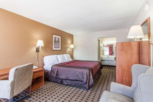默夫里斯伯勒Knights Inn Murfreesboro的酒店客房,配有一张床、一张桌子和椅子