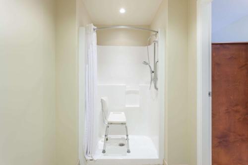 阿伯茨福德阿伯茨福德速8酒店的浴室内带椅子的白色淋浴