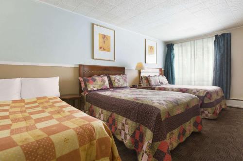 CochraneTravel Inn Cochrane的酒店客房设有两张床和窗户。