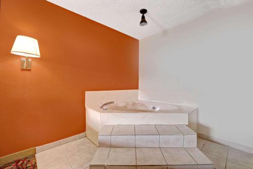 达拉斯达拉斯速8酒店的浴缸位于带橙色墙壁的房间内