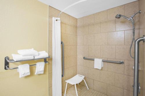 克莱夫Super 8 by Wyndham Clive IA的浴室内设有带白色凳子的淋浴