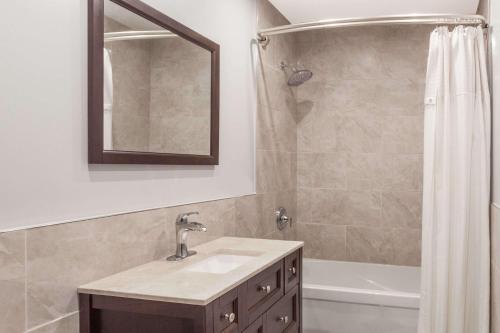 金斯顿金士​​顿骑士旅馆的浴室配有盥洗盆和带镜子的淋浴