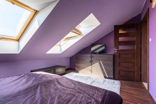 格里兹鲍Apartament Osiedle Bałtyk的一间紫色卧室,配有一张床和一台电视