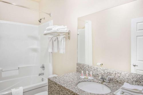 Peace RiverHigh Point Inn & Suites Peace River的一间带水槽、浴缸和镜子的浴室
