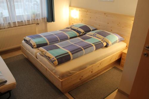 蒂罗尔州圣约翰芭芭拉公寓酒店的一间卧室配有一张带两个枕头的木床