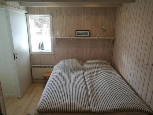 StillingsönÅsarna Hills Holiday Home Stillingsön的窗户房间里一张条纹床