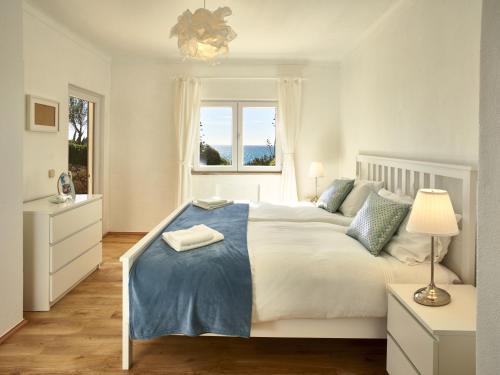 阿玛考德佩拉E&M Beach House Aldeamento do Levante I的一间卧室配有一张大白色床和蓝色毯子