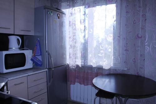 Leninsk-KuznetskiyОднокомнатная квартира的厨房配有桌子、微波炉和窗户。