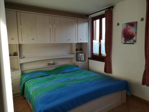MontagnolaCasa Olivo的一间卧室配有一张带蓝色床单的床和一扇窗户。