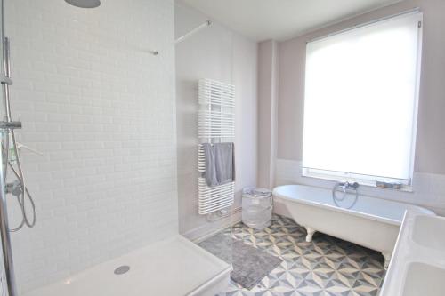 布鲁塞尔花园旅馆的白色的浴室设有浴缸和窗户。