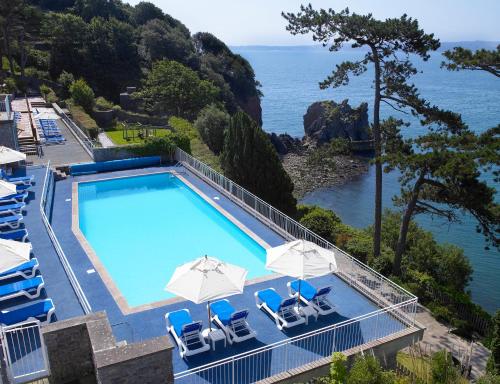 托基托基帝国酒店的毗邻大海的带椅子和遮阳伞的游泳池