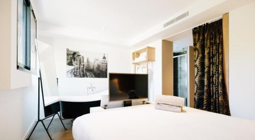 维琪奥港Citta di Lume Suites & Lofts的卧室配有白色的床和电视。