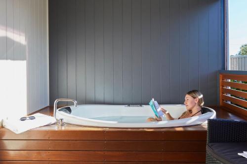 巴瑟尔顿BIG4 Breeze Holiday Parks - Busselton的坐在浴缸里读书的女人