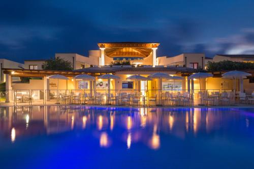 圣特奥多罗Grande Baia Resort & Spa的夜间带椅子和遮阳伞的度假村