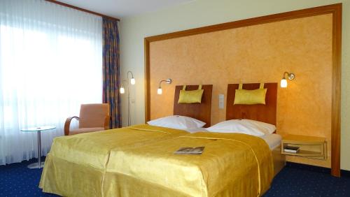 波茨坦阿斯科特布里斯都酒店的酒店客房设有一张大床,床罩是黄色的