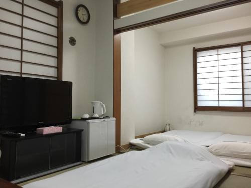 东京新大久保石亭酒店的一间卧室配有两张床和一台平面电视